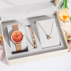 A luxury watch, bracelet, and necklace set in a cream-colored gift box. The set features a rose gold mesh watch with a vibrant orange dial, a matching rose gold bracelet with 'DAVID YEE' engraved on the band, and a delicate rose gold necklace with a round pendant displaying 'DAVID YEE' lettering.