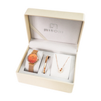 A Mibom jewelry gift set displayed inside an open cream-colored presentation box. The set includes a rose gold mesh-band watch with a round orange dial, a slim rose gold bracelet, and a delicate rose gold necklace with a white circular pendant, all arranged on white display cards.