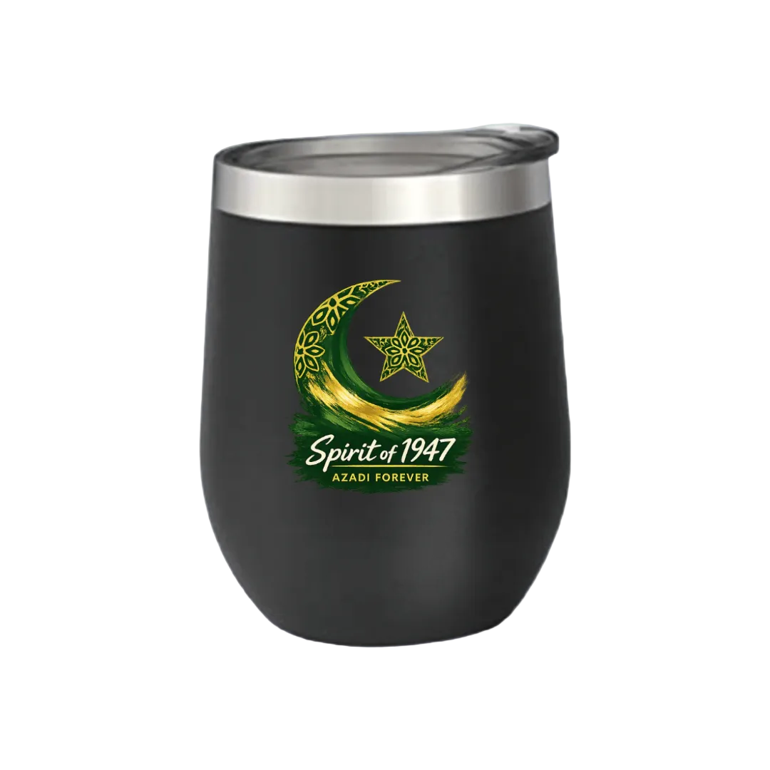 A matte black insulated stemless tumbler with a clear lid, featuring a green and gold crescent moon and star graphic with the text 'Spirit of 1947' and 'AZADI FOREVER' on the front, set against a solid light green background.