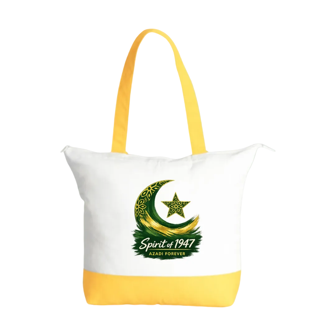 A white canvas tote bag with bright yellow handles and a yellow bottom panel, featuring a green and gold crescent moon and star graphic with the text 'Spirit of 1947' and 'AZADI FOREVER' on the front, set against a solid light green background.