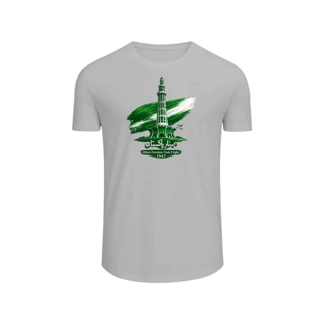 A light gray short-sleeve t-shirt with a green and white graphic print of the Gaddafi Tower in Libya, featuring a stylized flag and Arabic text, displayed on a light green gradient background.