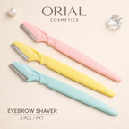 Three Orial Cosmetics eyebrow shavers in pastel pink, yellow, and light blue, arranged diagonally on a light beige textured background with decorative props and product text.